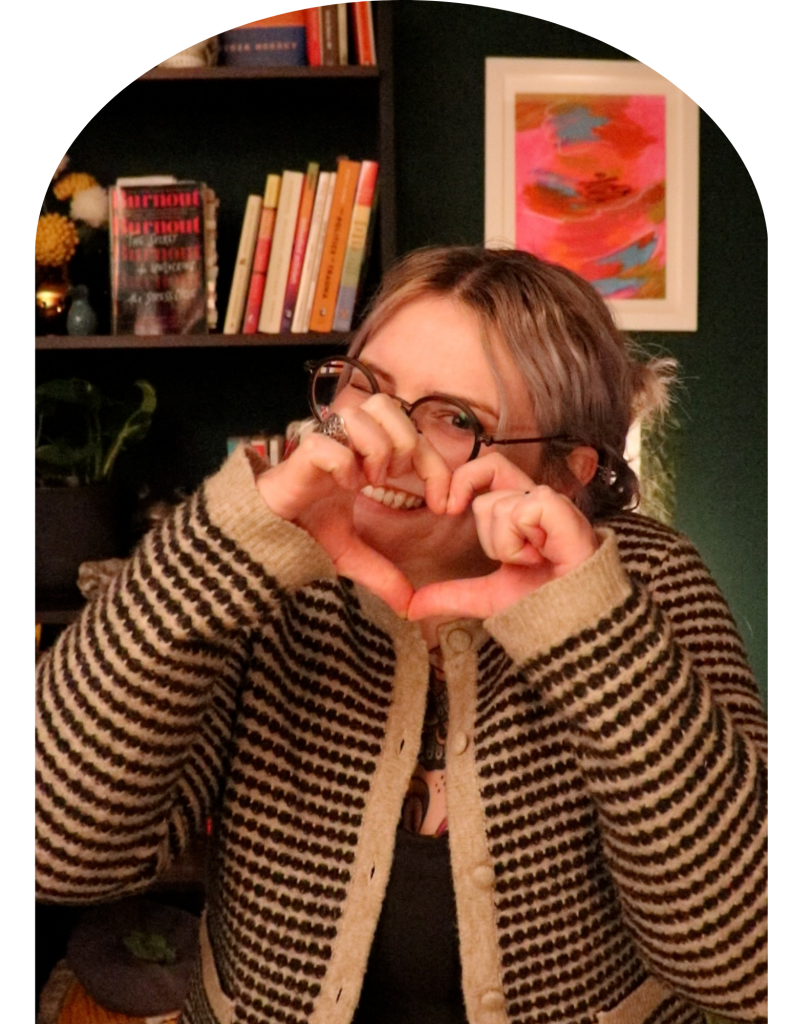 queer woman makes a heart with hand in her treatment room